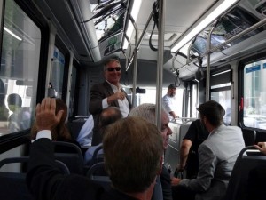 Photo of Mayor Dyer waving to passengers inside of electric bus.