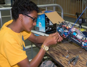 Student repairing remote controlled RC car sitting at table.