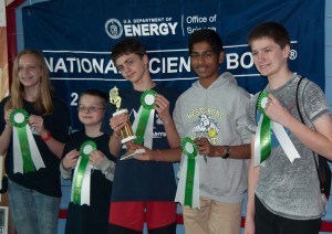 Students holding green and white ribbons in front of National Science Bowl backdrop.