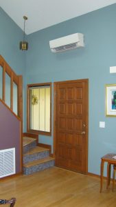 Mini split air conditioning fan above interior house door near stairway, photo.