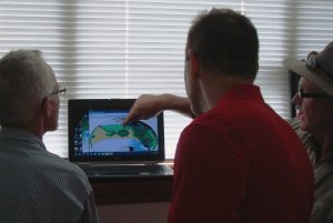 Two FSEC employees review solar access maps with business owner.