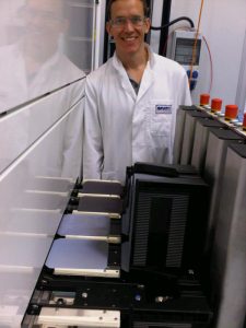 UCF researcher, Kris Davis, stands next to the ACPVD system that deposits metal oxide material onto silicon wafers.