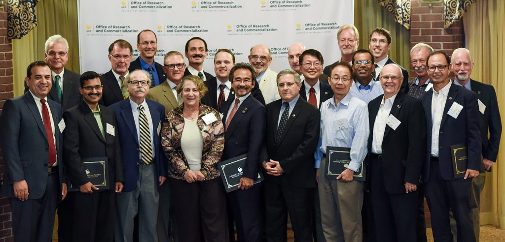 Group photo of inductees into National Academy of Inventers UCF Chapter. UCF Office of Research and Commercialization backdrop behind members.