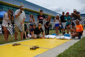 Two JSS cars finish within inches at finish line of race on yellow track.