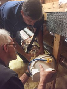 UCF/FSEC researchers Chuck Withers and Dave Chasar installing a mechanical ventilation control unit on a flexible duct.