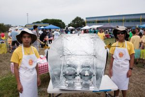 Two male students stand along side their foil-lined, foldable cooker that has two side-by-side insulated pots in the center.