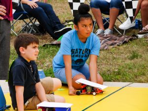 Female student from Saturn Elementary School and a male student prepare to race their Junior Solar Sprint cars, which were modified to run on batteries instead of solar due to the cloudy sky.