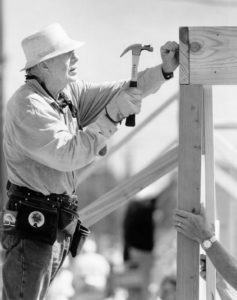 Former President Jimmy Carter hammering a nail into frame of new construction home.